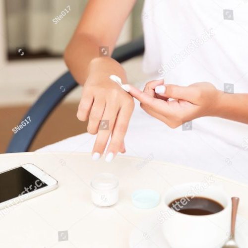 stock-photo-cropped-image-of-female-hands-applying-cream-at-the-hotel-terrace-phone-and-a-cup-of-coffee-on-the-1628523211